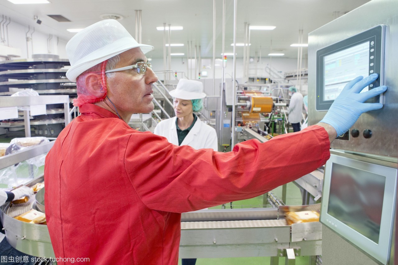 在奶酪加工廠生產(chǎn)線控制面板上的工人